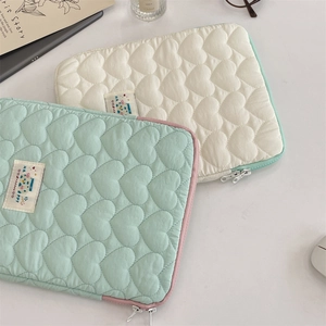 Detalle de fundas acolchadas para portátil con diseño de corazones y cremalleras de colores