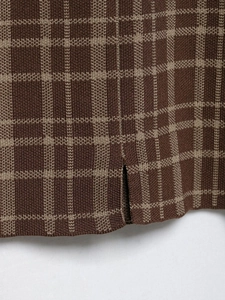Detailaufnahme von braunem Strick mit Karomuster und seitlichem Saumschlitz