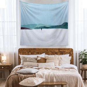 Detail of minimalist landscape tapestry showing mountains and a figure in a cozy bedroom