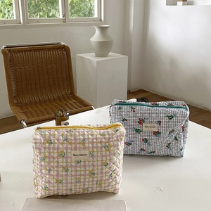 Detail of quilted floral and checkered pouches with zippers and woven labels