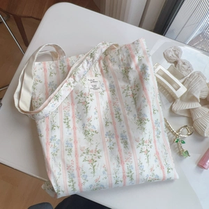 Vista piatta di una borsa tote in cotone floreale con strisce rosa e etichetta tessuta