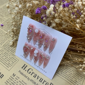 Detail of almond-shaped press-on nails with 3D white camellia and sparkling crystals