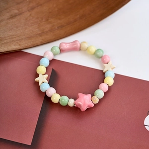 Close-up of colorful ceramic beaded bracelet with pink bow and beige star details