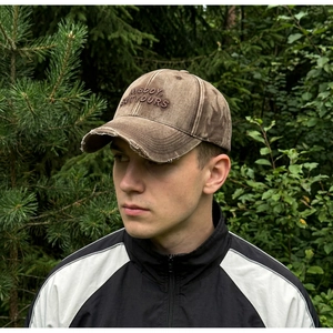 Detail of vintage washed brown baseball cap with embroidered letters and distressed brim