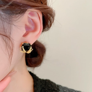 Close-up of vintage black rhinestone stud earrings with golden wheat ear detail on model