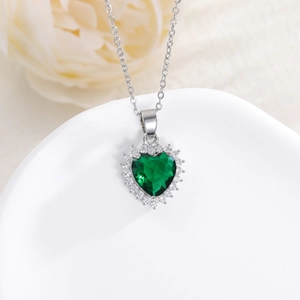 Detailed close-up of heart-shaped green gemstone necklace with white zircon halo inlay
