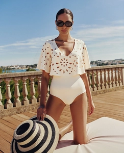 Detail of cream white one-piece swimsuit with intricate laser-cut floral hollow out design