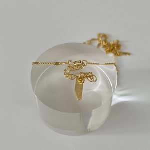Close-up of gold 925 sterling silver necklace featuring an engraved authenticity tag