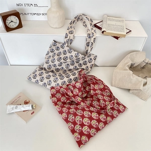 Close-up of vintage floral canvas tote bags in blue and red patterns on a styled desk