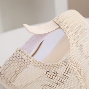 Macro detail of breathable mesh fabric and adjustable velcro strap on the beige baseball cap