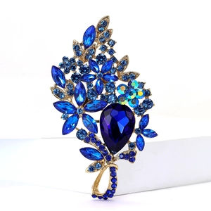 Detailed view of a gold alloy flower brooch with blue rhinestones and crystal drop