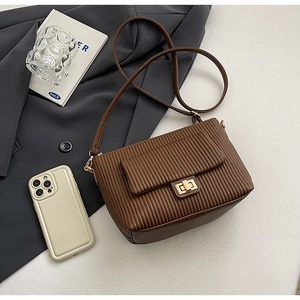 Détail du sac bandoulière plissé en cuir marron foncé avec fermoir rotatif en métal doré