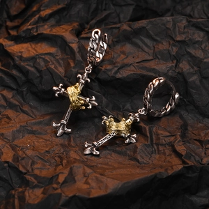 Detail of vintage silver cross earrings with gold crown accents on dark textured background
