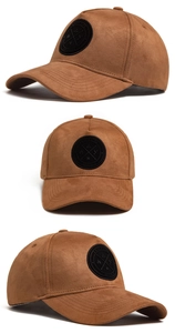 Dettagli di un cappellino da baseball in camoscio marrone con toppa rotonda in pelle nera