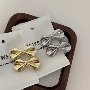 Detailed view of polished gold and silver metal bow hair clips on jewelry display card