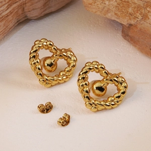 Vue détaillée des boucles d'oreilles cœur dorées avec texture torsadée sur bois