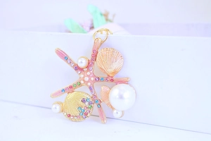 Close-up of pink star and shell keychain with crystals and pearls on white box