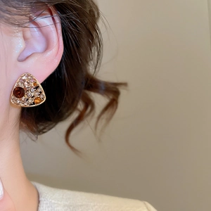 Detailed macro shot of vintage hollow triangle earrings with colorful crystals on a model