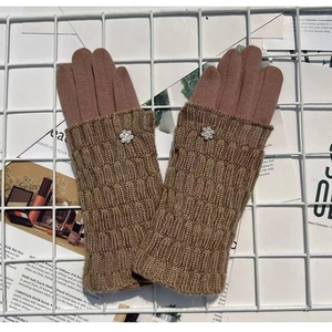 Detailed view of brown knit gloves with delicate flower embroidery on a grid display
