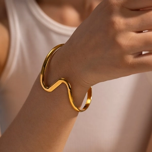 Minimalist 18K gold plated stainless steel wave bangle with a polished mirror finish