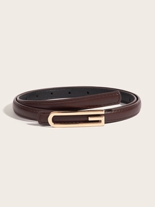 Close-up of slim dark brown leather belt with elegant golden G-shaped buckle detail