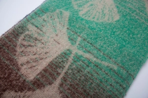 Close-up of turquoise and beige ginkgo leaf jacquard woven fabric with soft texture