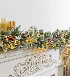 Detail of Christmas garland with lamb's ear leaves, red berries and warm LED lights
