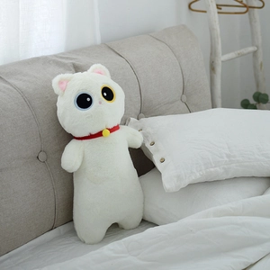 Gros plan d'un coussin chat en peluche blanche avec des yeux vairons et un collier à clochette