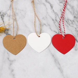 Macro shot of heart-shaped paper gift tags in brown, white, and red with rustic twine strings