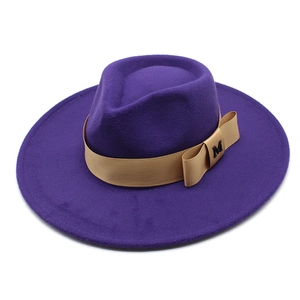 Detail of purple wool fedora hat featuring a camel ribbon with a gold M logo bow