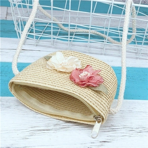 Détail d'un sac en paille tressée avec fleurs et bandoulière en coton pour plage et été