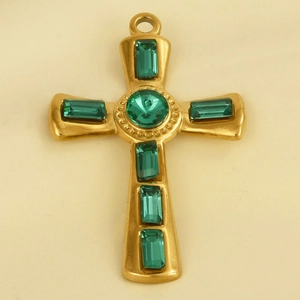 Close-up of golden cross pendant with a central round green gem and emerald-cut stones
