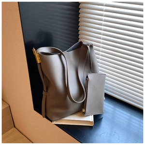 Close-up of grey pebbled leather tote bag with gold lock detail and matching small pouch