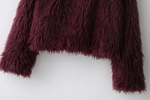Detailed close-up of dark wine red faux fur coat showing texture on hem and cuffs