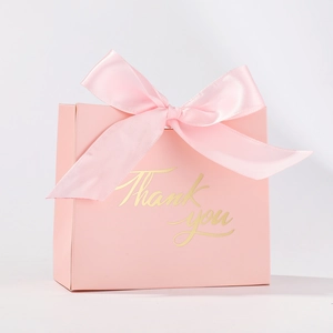 Pink cardboard favor box with a satin ribbon bow and gold foil Thank You lettering