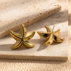 Minimalist gold starfish stud earrings made of polished stainless steel on stone