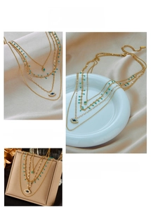 Detail of triple-layer gold chain necklace with evil eye pendant and turquoise beads