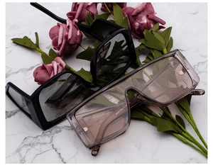 Close-up of black and brown vintage sunglasses on marble background with rose decoration