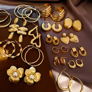 Detailed collection of vintage gold geometric earrings and pearls on brown silk fabric