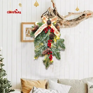 Hanging Christmas wreath with red berries, pine cones and LED lights on wooden wall