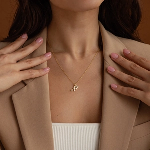 Elegant gold stainless steel letter M necklace with small heart charm on model