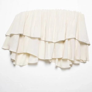Flat lay of cream layered ruffled tube top with delicate silver beaded trim detailing