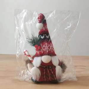Close-up of a Christmas gnome plush with a red checkered body and knit hat in packaging