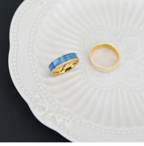 Macro detail of blue marble enamel and white painting on gold plated titanium rings