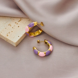 Pink and purple enamel C-shaped hoop earrings with gold finish on silk background