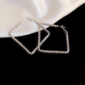 Detail shot of oversized silver-toned square earrings with textured metallic finish