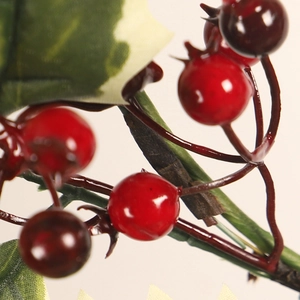 Artificial Christmas wreath branch with vibrant red berries and green leaves for decoration