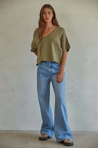 Full view of high waist wide leg light blue jeans paired with olive green knit top