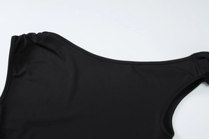 Detailed view of black asymmetric neckline and shoulder texture on a slim summer outfit