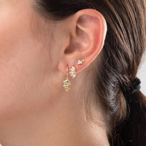 Detail shot of gold-plated earrings set with turquoise and zircon on female ear